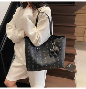 Dettaglio della borsa tote monogramma con cinturini in pelle e ciondolo a cucciolo nero
