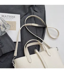 Detail of adjustable long shoulder strap on a white lychee grain leather bucket bag
