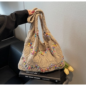 Close-up of beige crochet knit tote bag with colorful beads and woven handle detail