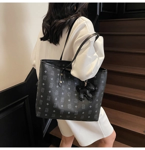 Dettaglio della borsa shopper monogramma nera con texture pelle e ciondolo a cucciolo