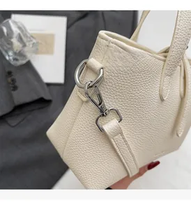 Detail of cream white leather bucket bag with lychee texture and silver metal hardware
