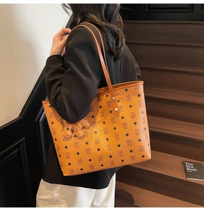 Dettaglio borsa tote in pelle marrone arancio con motivo monogramma e ciondolo a mano
