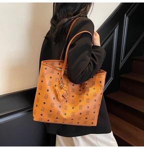 Vista dettagliata di una borsa tote marrone in ecopelle con monogramma di orso e ciondolo