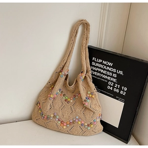 Detail of beige crochet tote bag with colorful faux pearls and knitted hollow texture