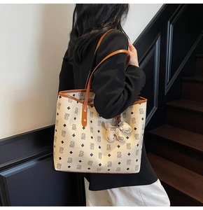 Dettaglio della borsa tote in pelle color panna con stampa orso e tracolla marrone