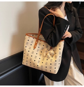 Dettaglio della borsa shopper monogramma crema con finiture in pelle marrone e ciondolo orso