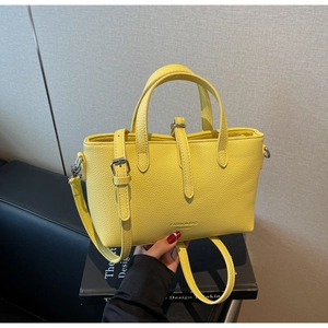 Detailed macro of bright yellow litchi pattern leather handbag with fashion metal buckles