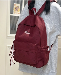 Detailed back view of a burgundy casual backpack with multiple pockets and white cords