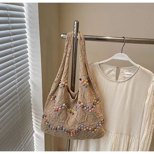 Close-up of beige crochet tote bag featuring multi-colored faux pearls and hollow knit detail