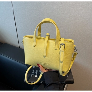 Detail of yellow bucket bag with lychee grain texture and dual handle design