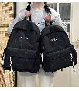 Detail of two black wash fabric backpacks with white zipper pulls and oval logo