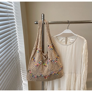 Detailed macro of beige crochet tote bag with colorful pearl beads and hollow weave pattern