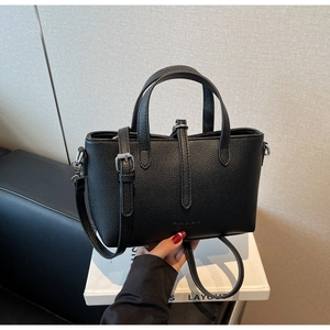 Close-up of black litchi texture leather bucket bag with dual handles and shoulder strap