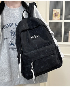 Detail of black canvas backpack with white rope zippers and minimalist logo on the front