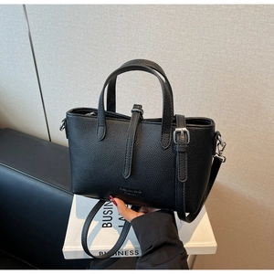 Detail of classic black lychee grain texture and metal buckle on the fashion handbag