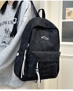 Close-up of black distressed texture backpack with white logo and zipper pull details