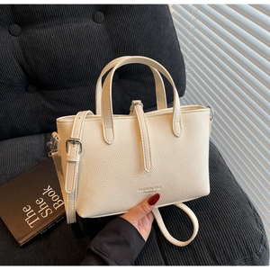 Detail of creamy white textured leather tote bag with elegant golden light and shadows