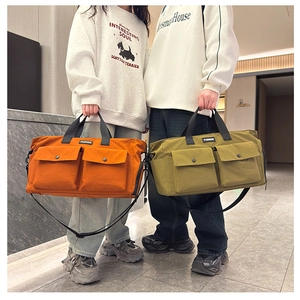 Detail of large travel bags in orange and green showing functional front pockets and nylon texture