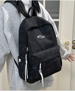 Detail view of the black backpack with marble pattern, white drawstrings and side pockets