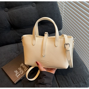 Close-up of cream textured leather bucket bag with silver hardware and fashion text