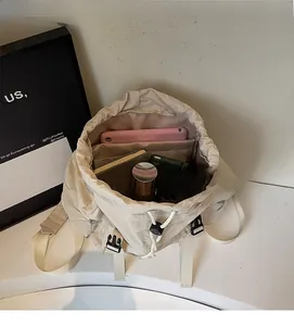 Top view showing spacious interior of beige drawstring backpack with laptop and essentials