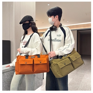Large travel duffel bag with dual front snap pockets in orange and olive canvas