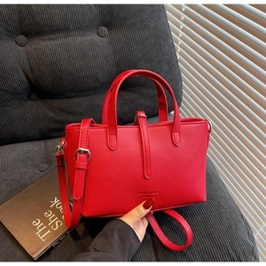 Detail of red pebbled leather handbag with silver hardware and adjustable strap