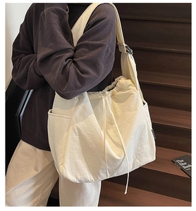 Detail of minimalist beige canvas shoulder bag with drawstring closure and side pockets