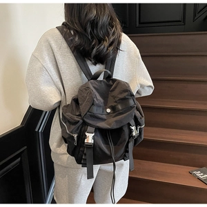 Close-up of black nylon backpack with metal buckle closure and side zipper detail