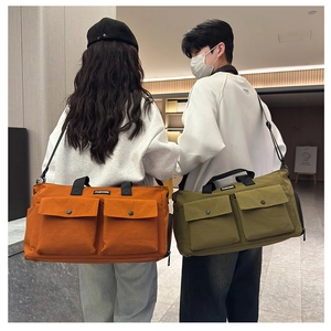 Detail view of orange and olive green travel bags with fashion label and shoulder straps