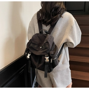 Detail of black nylon backpack with silver metal buckle and side zipper on a modern staircase