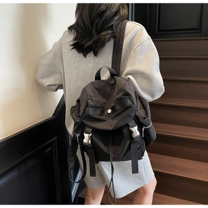 Detail view of the black nylon backpack with silver metal buckles on wooden stairs