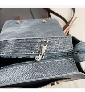 Detailed macro view of the smooth metal zipper on this blue denim texture shoulder bag