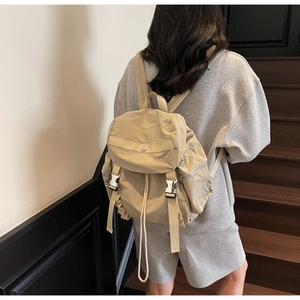 Detail of khaki nylon backpack featuring flap closure and adjustable side buckle straps