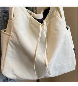 Detail view of large cream canvas tote bag showing drawstring closure and side pockets