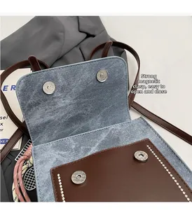 Detail of strong magnetic snap closure on light blue denim bag with brown leather flap