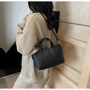 Close-up of black lychee grain leather bucket bag with adjustable crossbody strap