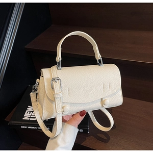 Dettaglio borsa a mano color crema in pelle martellata con tracolla e patta di chiusura