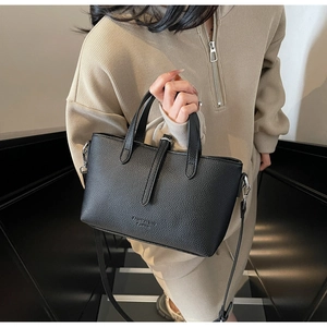 Detail of black lychee grain leather handbag with dual handles and slim shoulder strap