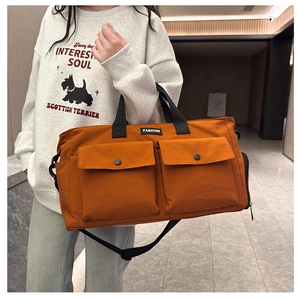 Detail of orange travel bag with two front flap pockets and adjustable black strap