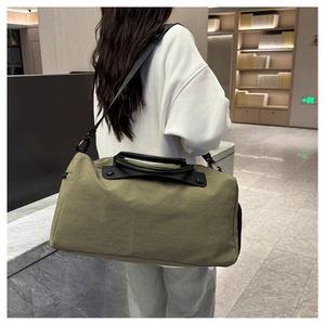 Crossbody view of an army green travel bag with black straps in a modern indoor setting