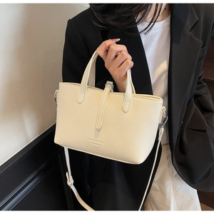 Detail of creamy litchi grain leather handbag with silver hardware and fashion embossing