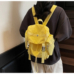 Rear view of a yellow wrinkled nylon backpack with silver buckles on a person
