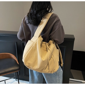 Detail view of the drawstring closure and side pocket on this large beige canvas tote bag