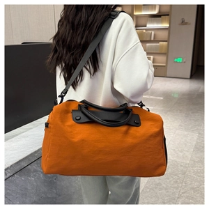Close-up of vibrant orange travel bag featuring black nylon straps and sturdy handles