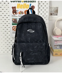 Detailed macro view of the QIJIAOYE logo and washed canvas texture on the black backpack