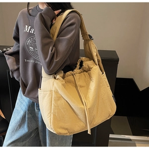 Detail view of khaki nylon crossbody bag featuring drawstring closure and wide strap