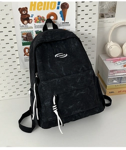 Detail of a washed black backpack with a retro texture and white decorative drawstrings