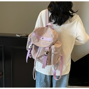 Rear view of model wearing a stylish pink nylon backpack with adjustable purple straps