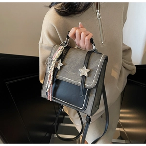 Détail du sac à dos en cuir gris avec étoile métallique et pendentif tissé